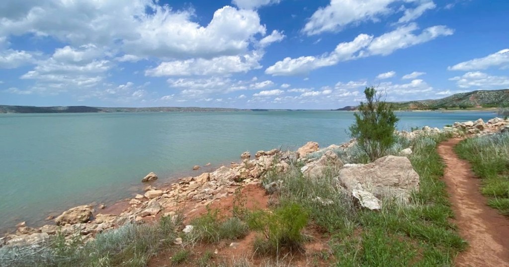 Views of the rocky shoreline along Lake Meredith in Texas, featuring calm blue waters and rolling hills in the backdrop.