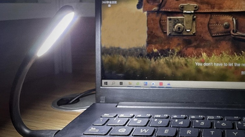 Flexible light plugged into a laptop shining over a keyboard