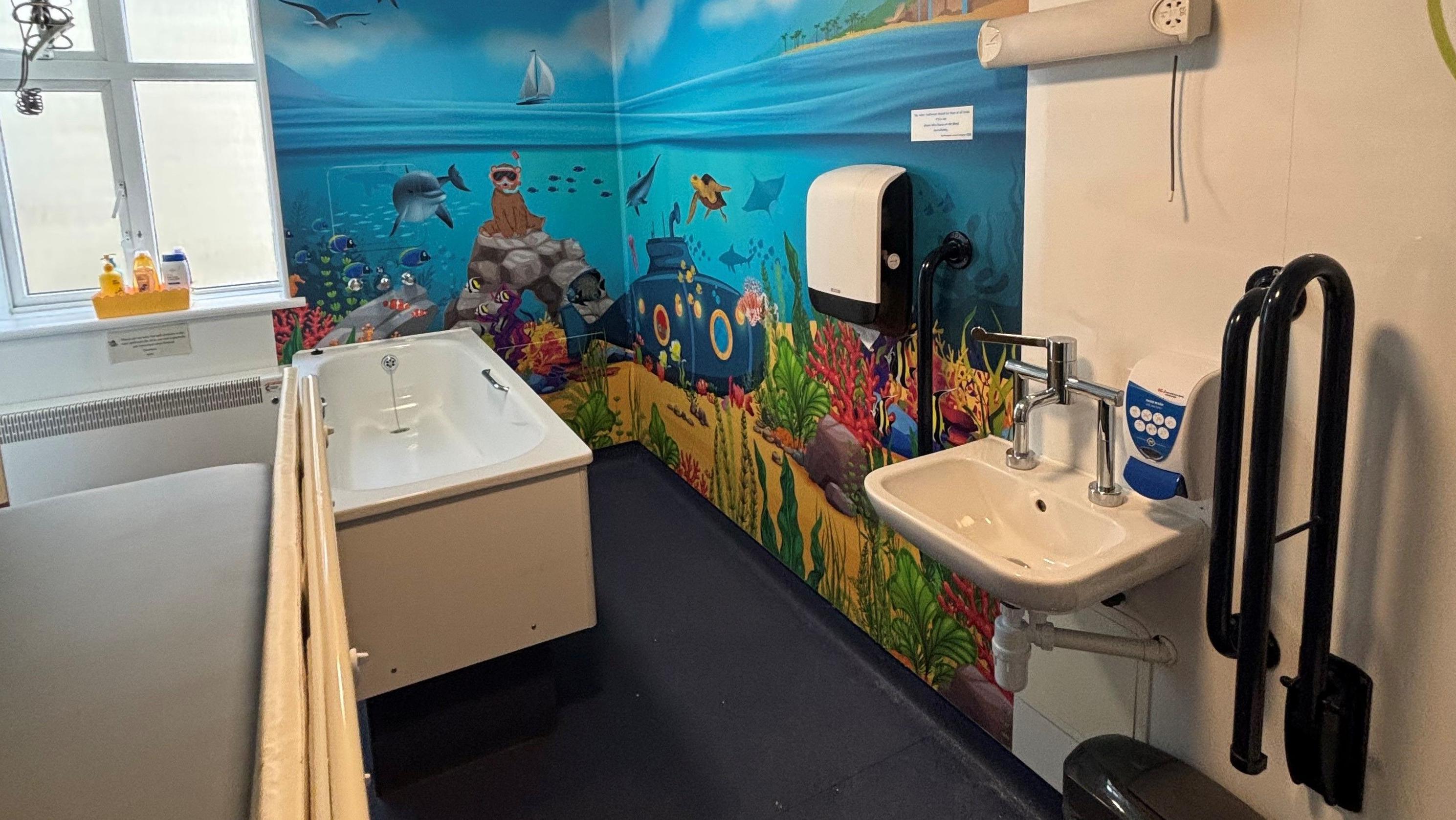The bathroom features a colourful seaside mural