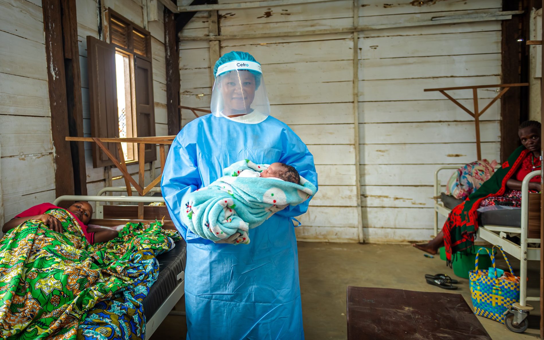Francine, a UNFPA-supported midwife at the health center in the Kigonze displacement camp, holds a newborn delivered safely at the camp clinic, during an outbreak of Ebola - Junior Mayindu/UNFPA DRC