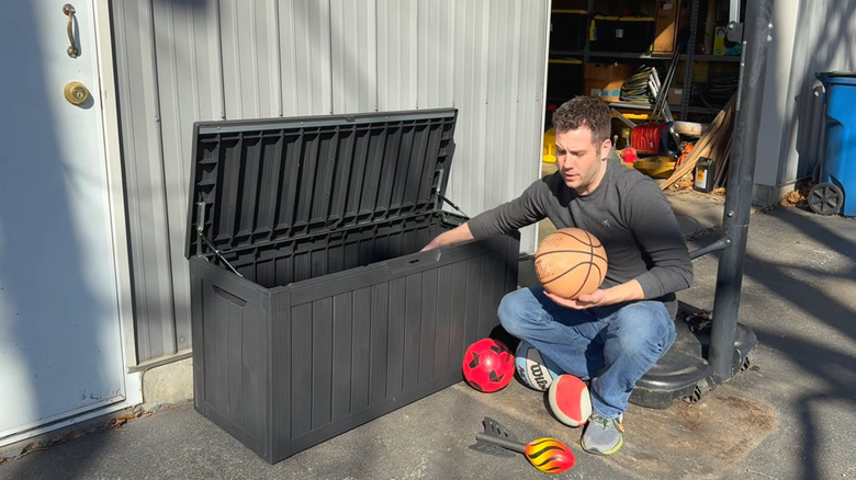 Man putting outdoor toys in a deck box