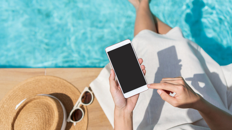 Woman using a smartphone poolside with the display off.