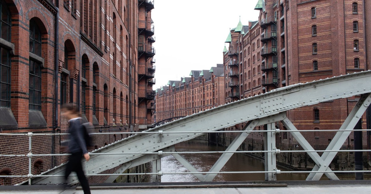 A person walks briskly on a bridge in Hamburg's iconic Speicherstadt district, showcasing historic brick architecture.