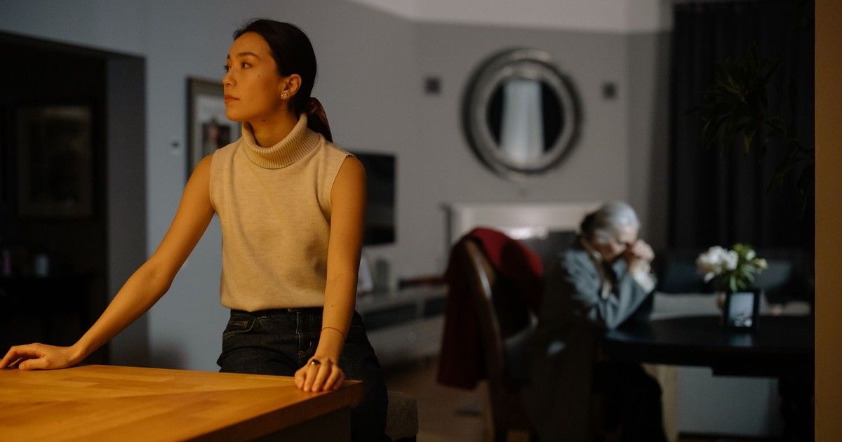 Tense moment between two women in a dimly lit living room, capturing emotion and introspection.