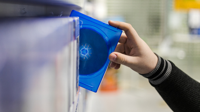 Person removing a DVD in a case from a shelf