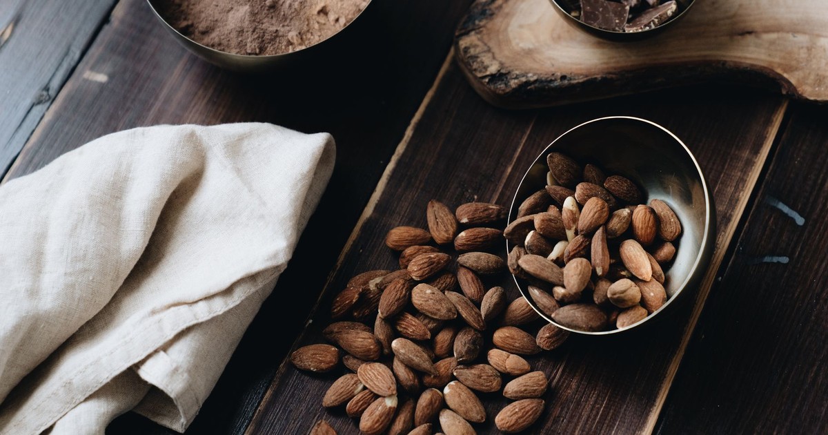 A still life composition with almonds, chocolate, and cacao powder on a wooden surface, creating a warm and delicious atmosphere.