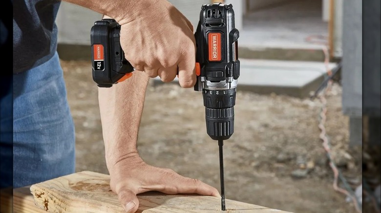 A person using the Warrior 12V cordless drill on a wooden board.