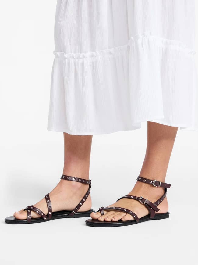 model wearing studded black sandals and a white midi dress