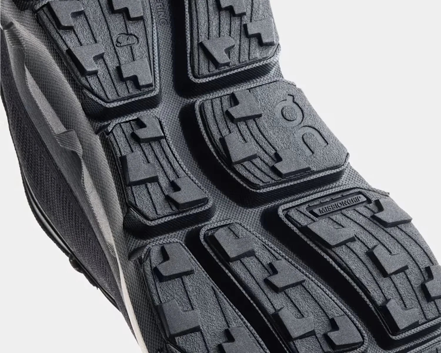 Close-up of black rubber outsole with raised tread patterns and "MISSIONGRIP" text on a shoe sole.