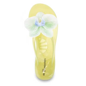Yellow flip-flop with a white orchid embellishment on the strap, labeled
