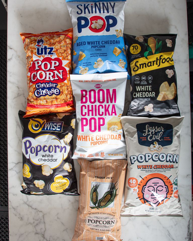 A variety of cheddar popcorn brands arranged on a surface