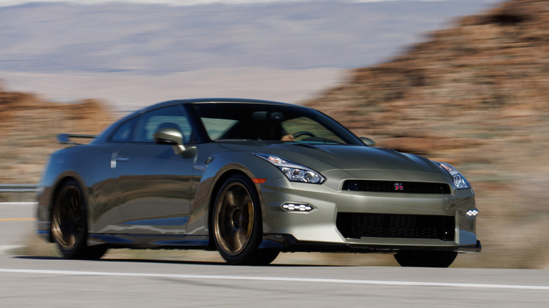 Front 3/4 view of 2024 Nissan GT-R driving on desert road.