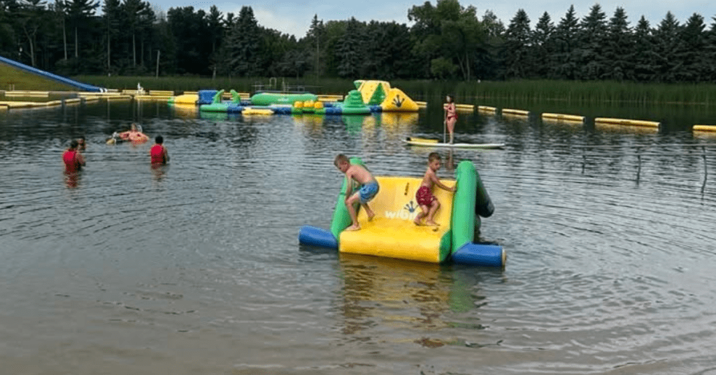 Children playing on an inflatable water park structure at Plamann Park lake in Wisconsin.