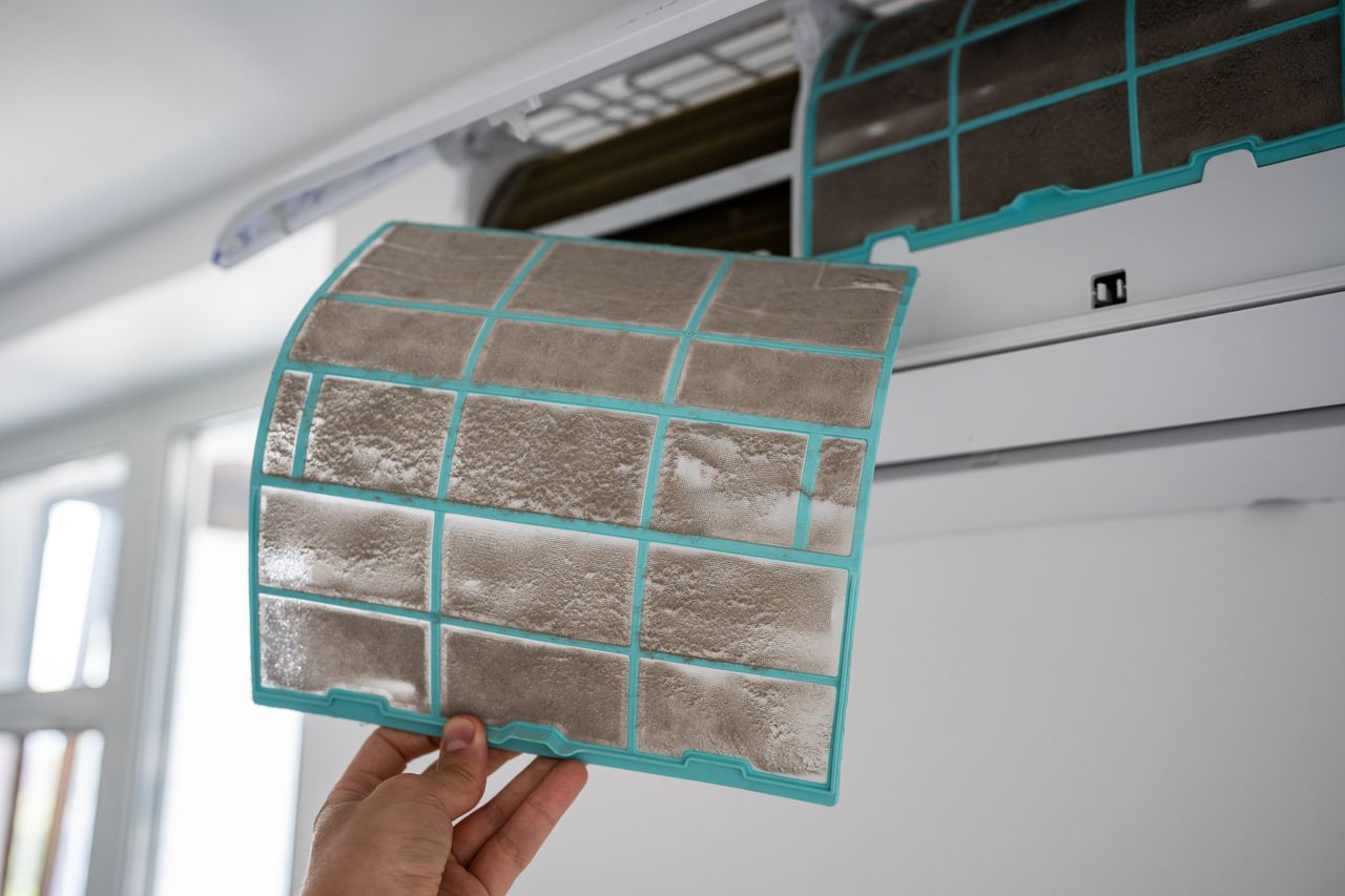 Closeup of person removing dirty dusty air conditioner coarse filter