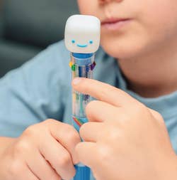 Child holding a multi-colored pen with a smiling topper, focusing intently. Text reads: