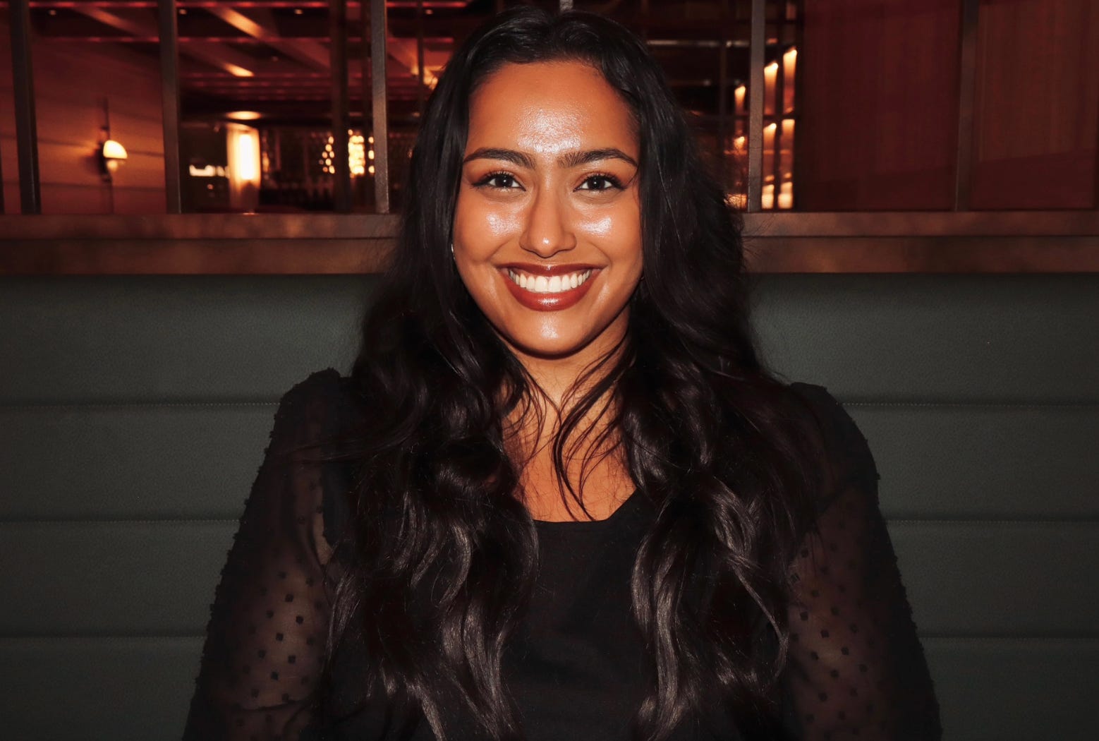The writer sitting in a black booth in a restaurant in Los Angeles.