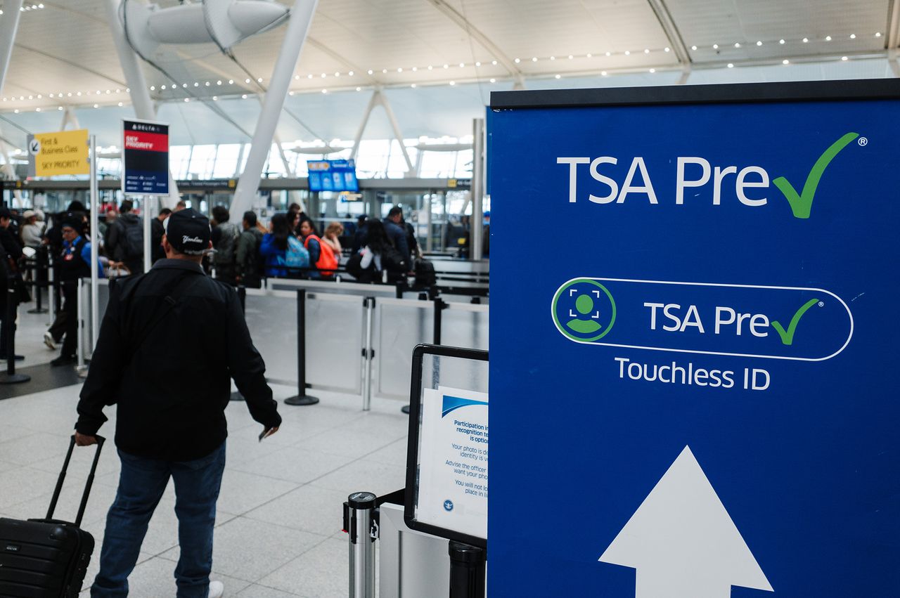 TSA PreCheck sign displaying Touchless ID with travelers in the airport background