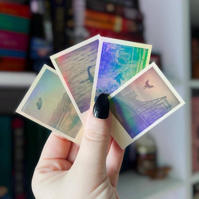Hand holding four small photos with indistinct, artistic scenes. Background includes colorful books on shelves