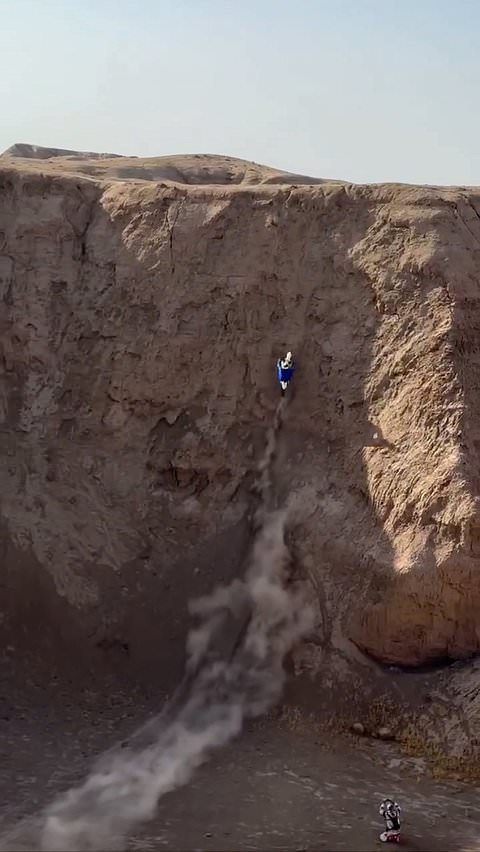 Motorbike rider climbs steep cliff in stunt