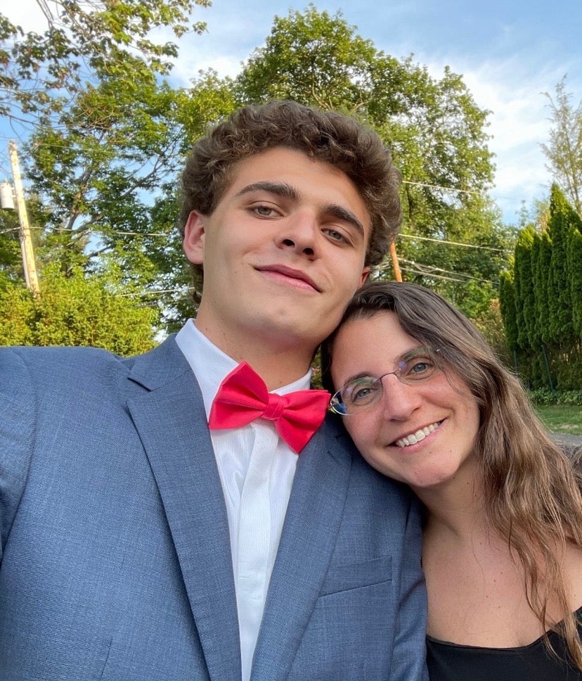 Eddie in a suit with a red bow tie smiling with his mom Christine outdoors