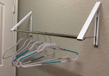 same reviewer's photo of the clothes rack with the clothing bar holding several empty hangers