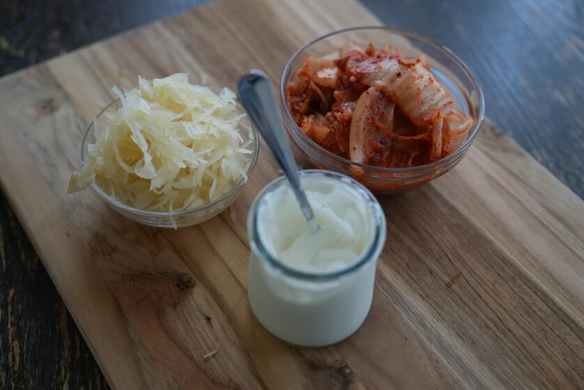 Kimchi, sauerkraut and yogurt in three separate glass containers on a table