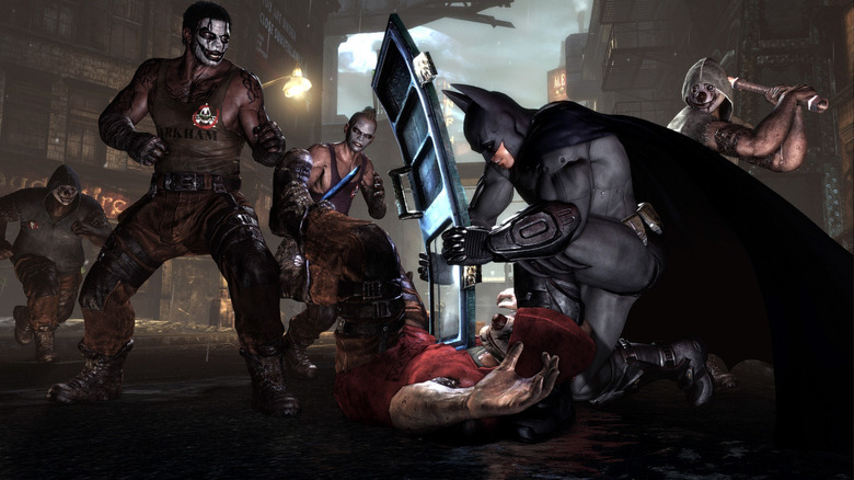 Batman hits a crook with a riot shield as other enemies watch in Batman: Arkham City