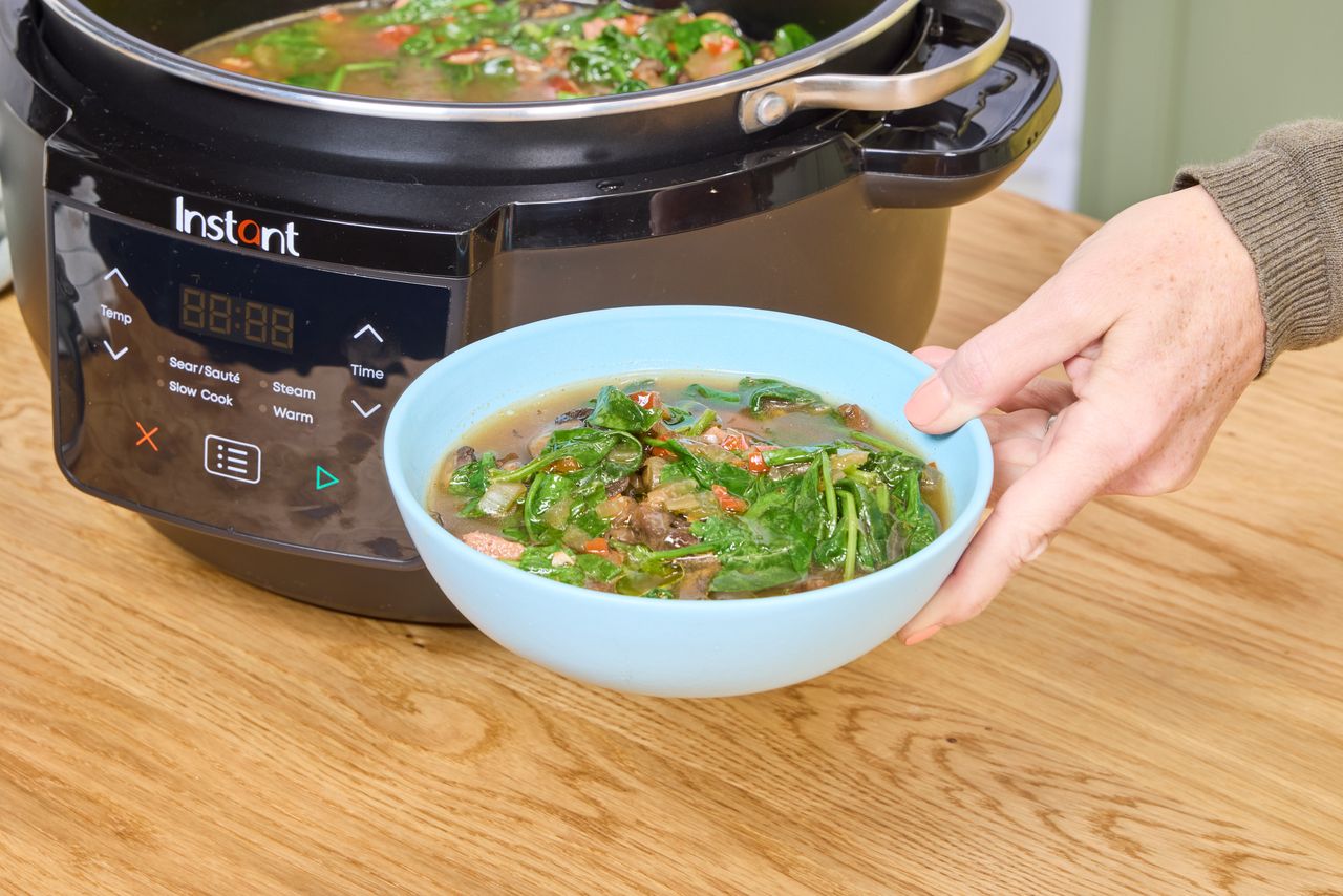 A person holds a bowl of soup cooked in the Instant Superior Cooker 7.5QT Slow Cooker