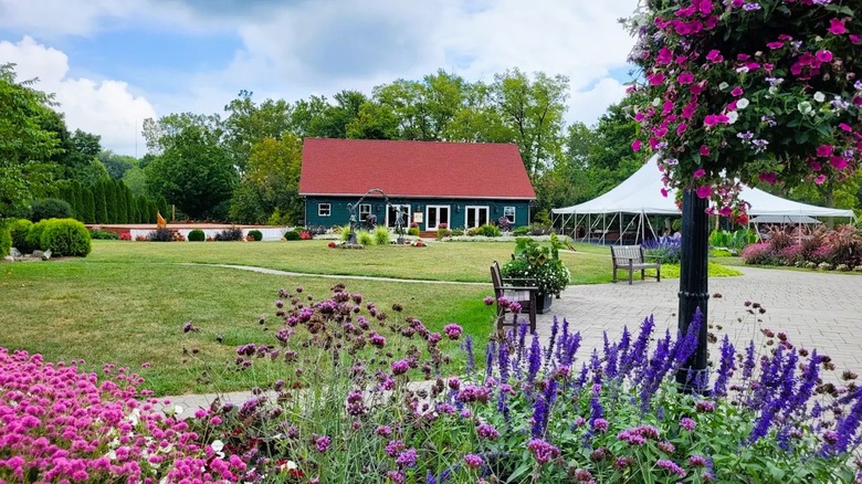 Matter Park in Indiana, featuring a vaulted-roof building, a tent, manicured lawns, benches, and framed by colorful blooms.