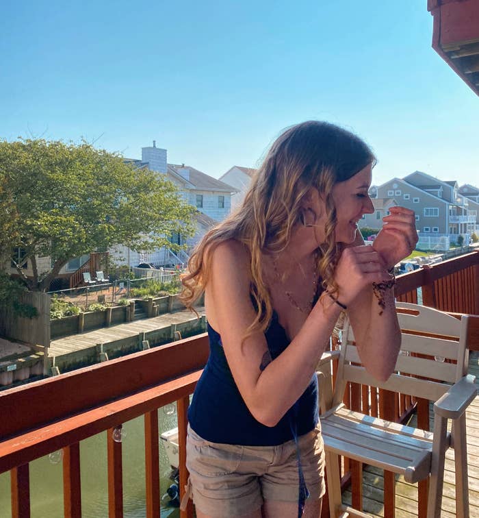 Me laughing on a balcony next to a dock with boats on a sunny day