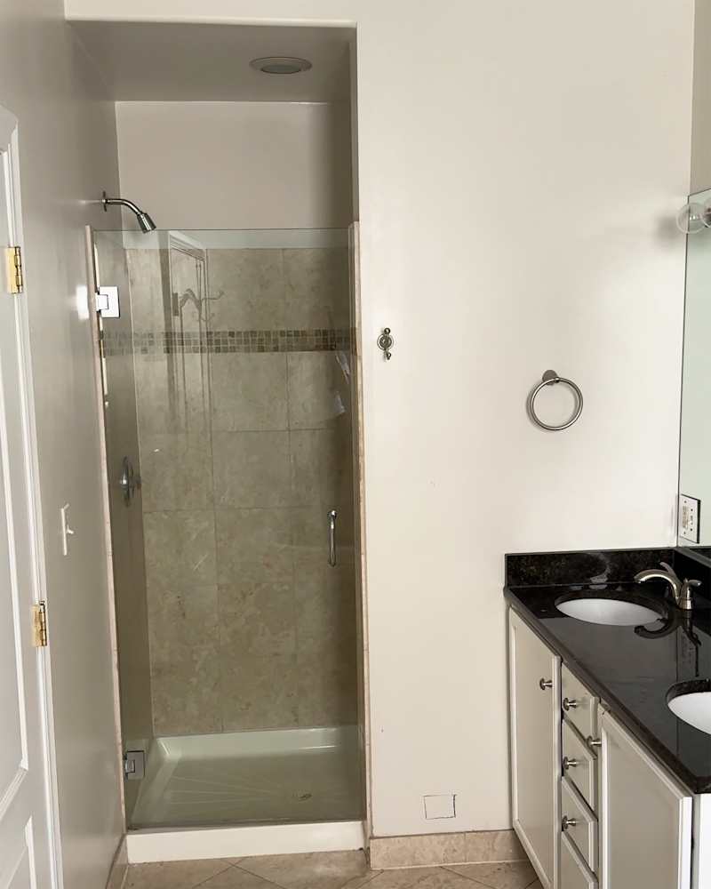 Dated bathroom shower before renovation.