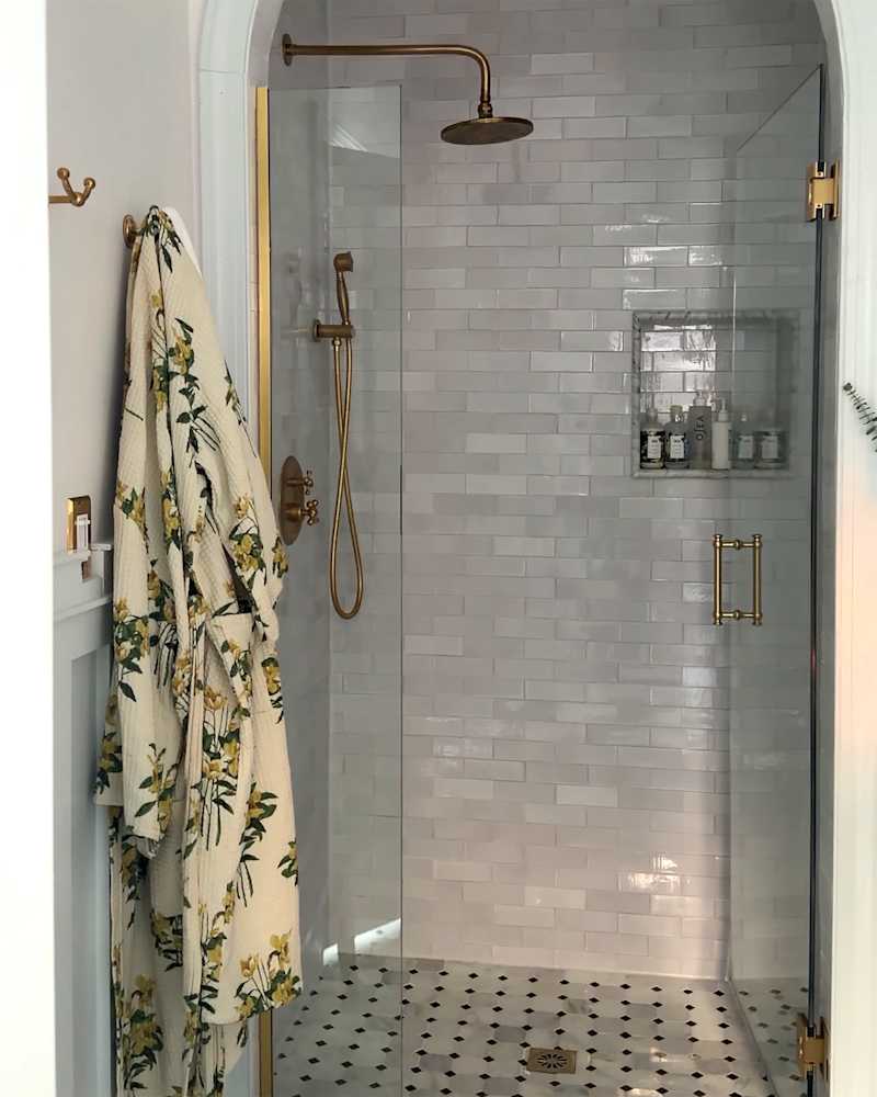 Grey tile in newly renovated bathroom with gold shower hardware.