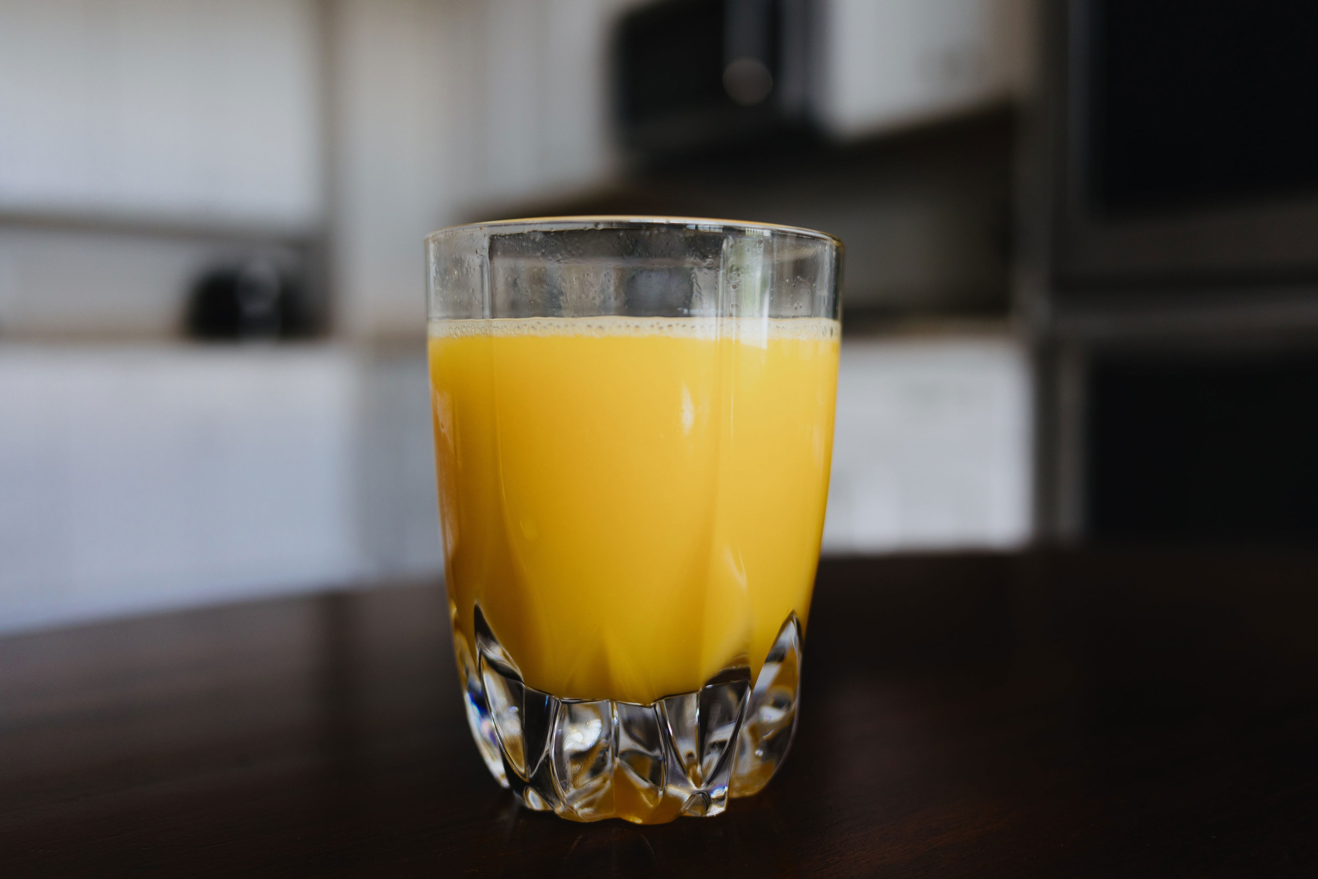 A glass of orange juice on a dark table in a kitchen setting