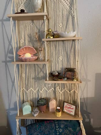 Boho-style hanging shelf with various decorative items, including a shell lamp, plants, and a Sweethearts candy box, suitable for home decor shopping