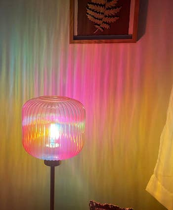 A decorative lamp with a textured glass shade casts rainbow patterns on a wall, creating a cozy ambiance in a home setting