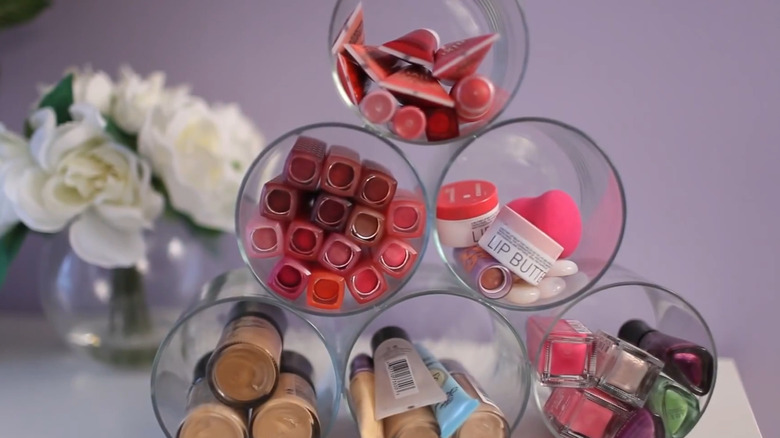 Stacked glass jar organizer filled with cosmetics sitting on a bathroom counter