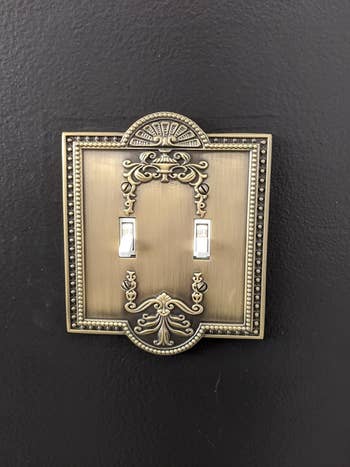 reviewer's close-up of brushed brass plate with pretty vintage design