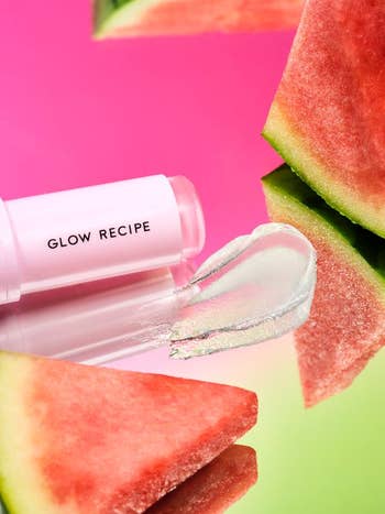 Lip balm from Glow Recipe displayed with watermelon slices on a reflective surface