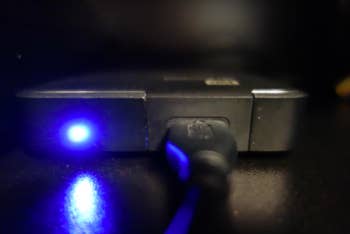 Phone connected to a charger with a glowing blue indicator light