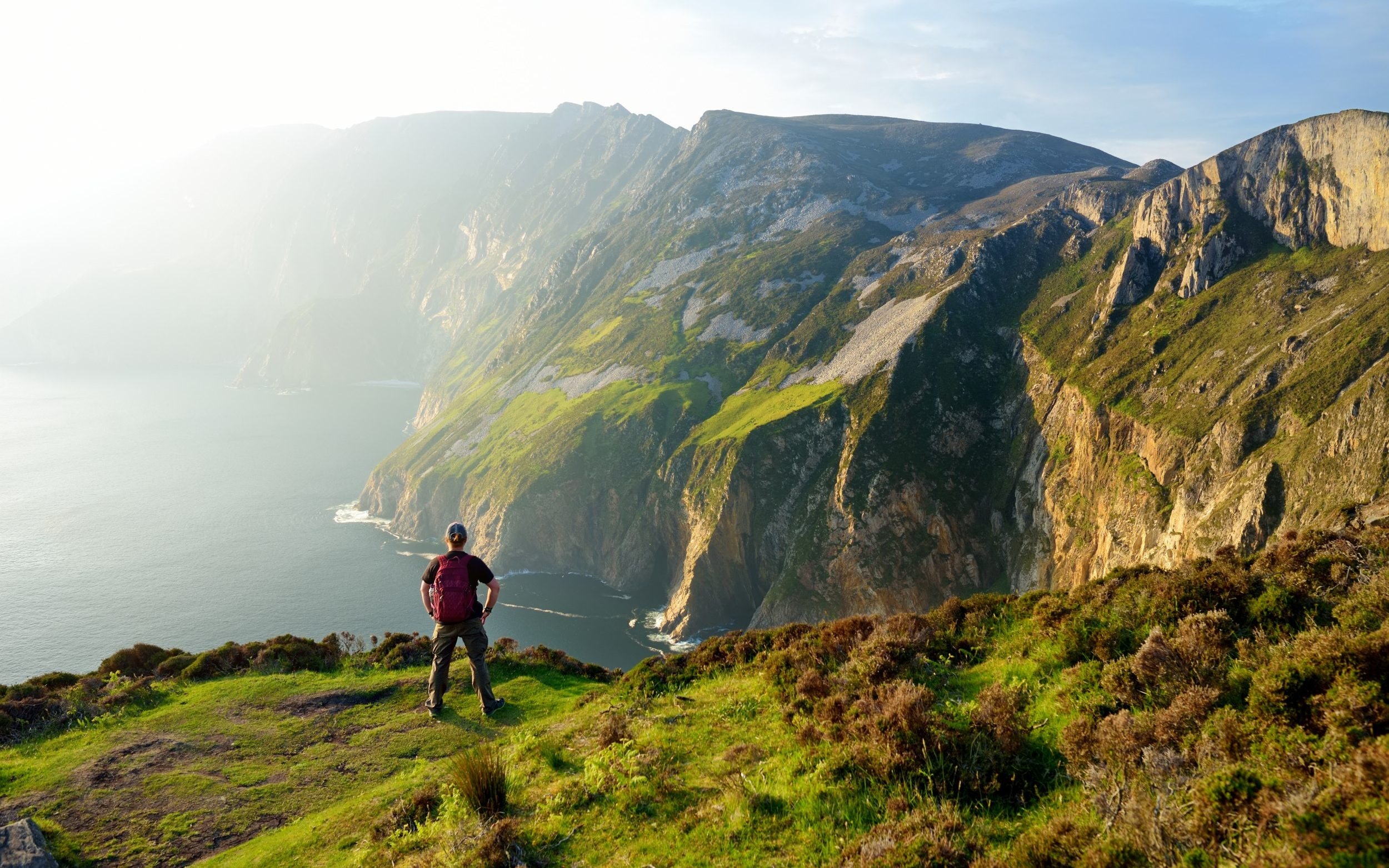 A man stands on a cliff admiring a view of Slieve League, Ireland's highest sea cliffs located in south-west Donegal