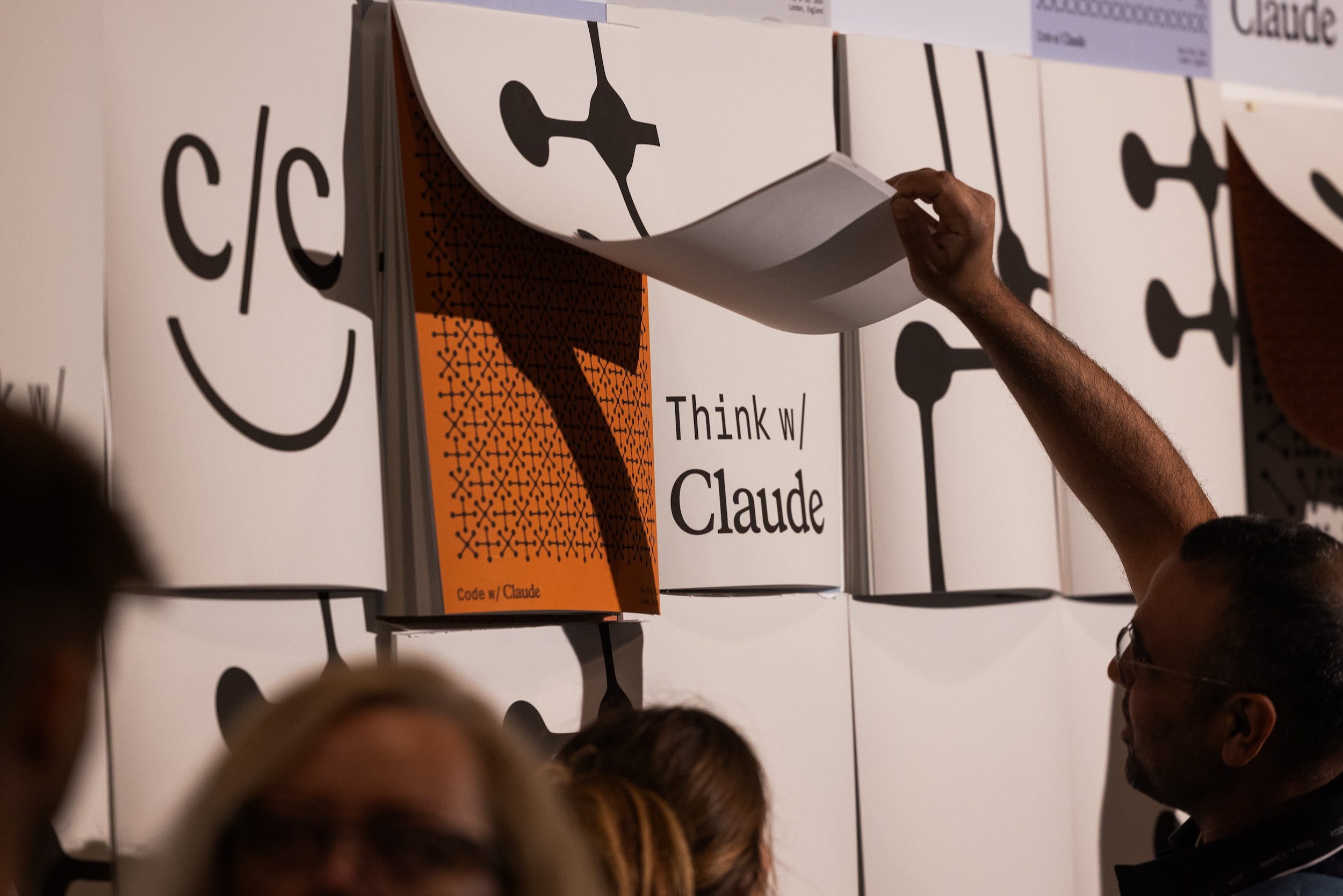 An attendee interacts with a removable poster at an Anthropic event