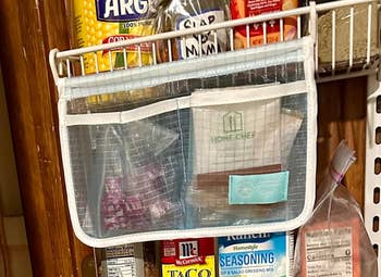 Pantry organization using a hanging mesh pocket with seasoning packets and canned goods visible on shelves