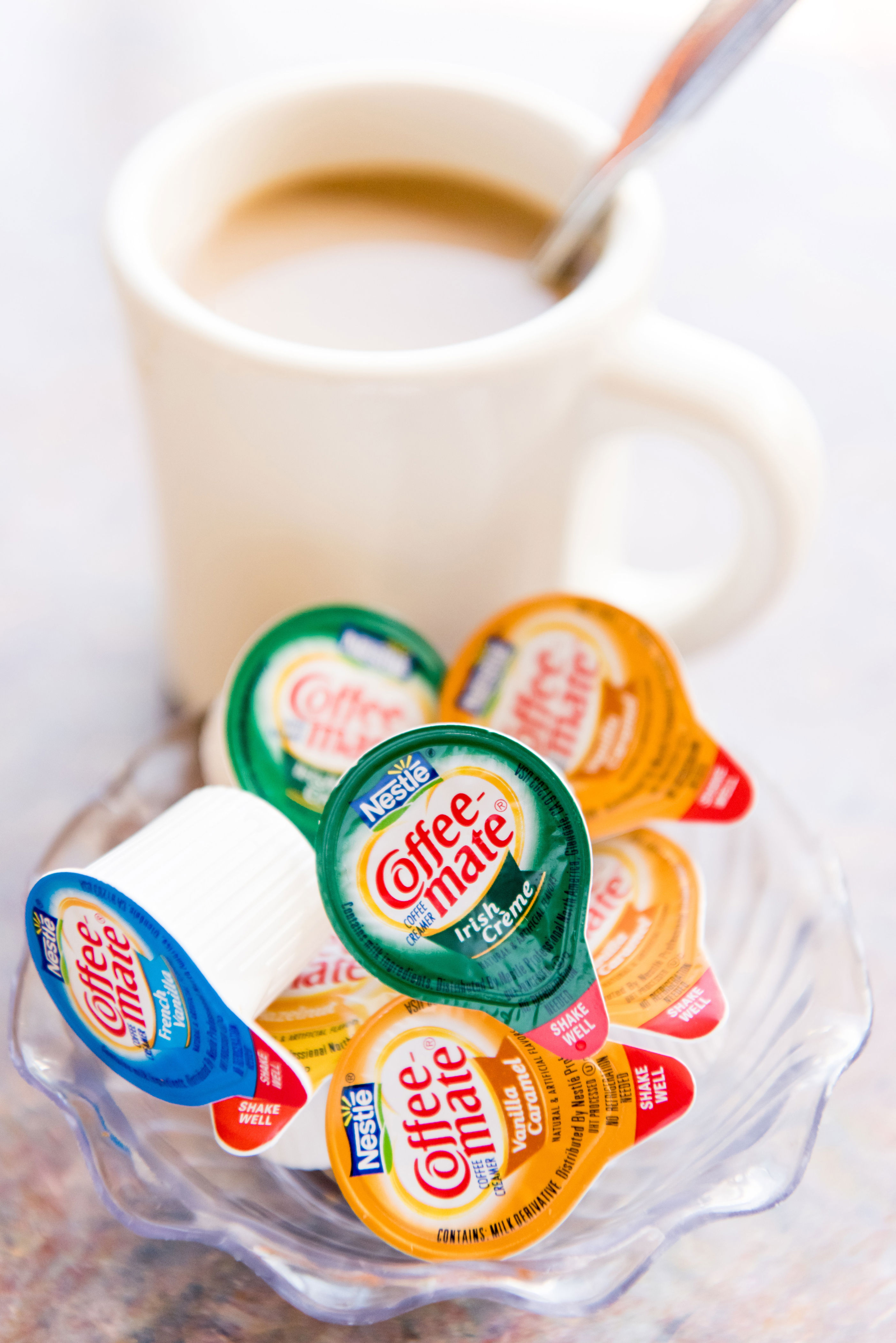 Mini coffee creamers next to a mug