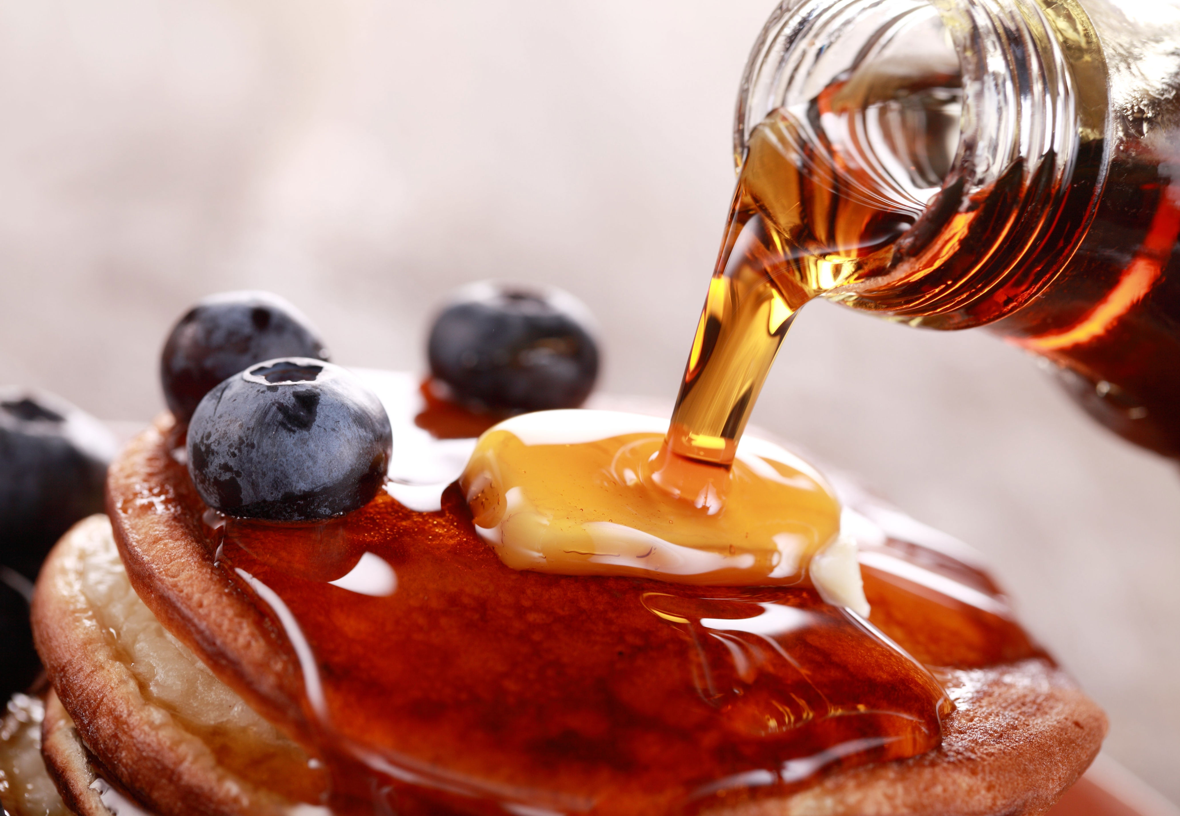 Pancakes topped with blueberries and butter, with syrup being poured over them