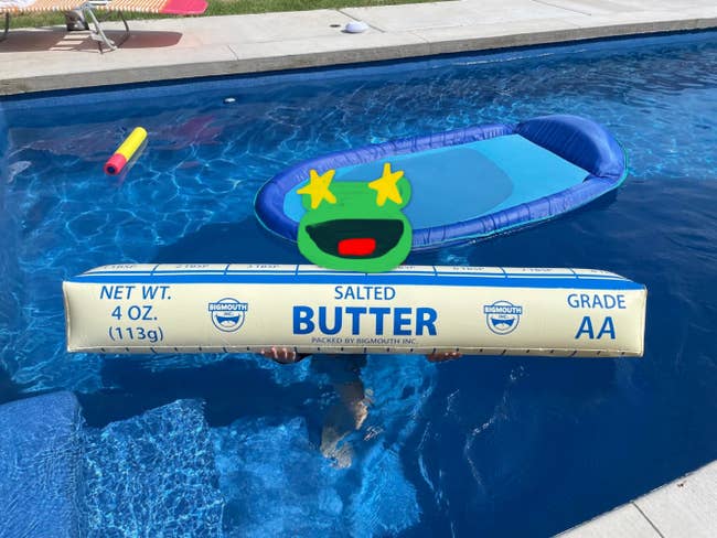 Child in a pool holds an oversized inflatable butter stick