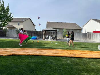 Four people play the game by throwing balls into pants