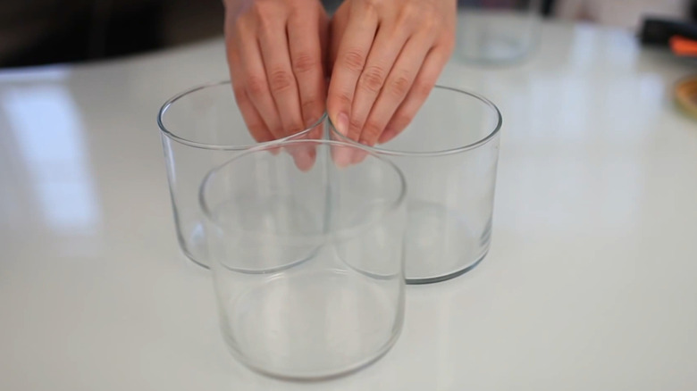 Person arranging three glass jars on a table