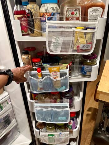 A well-organized refrigerator door filled with various condiments, sauces, and jars. A hand is pointing at an item on the middle shelf