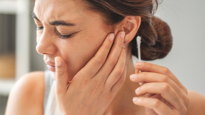 Woman using a cotton swab in her ear
