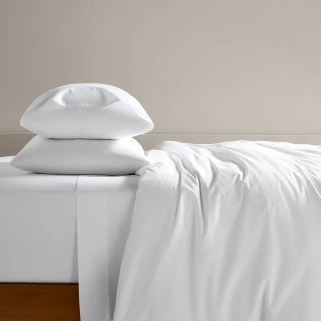 Stacked white pillows on a neatly made bed with a slightly wrinkled duvet, creating a cozy atmosphere